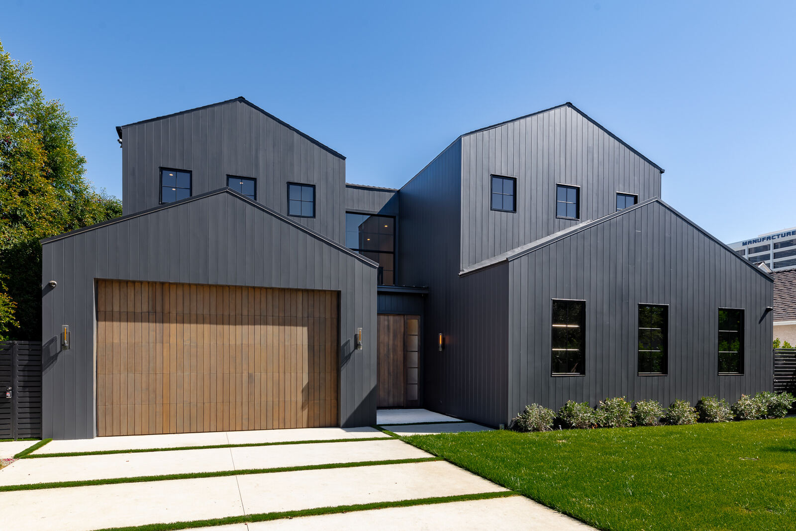Charcoal modern home exterior with wood garage door in Los Angeles