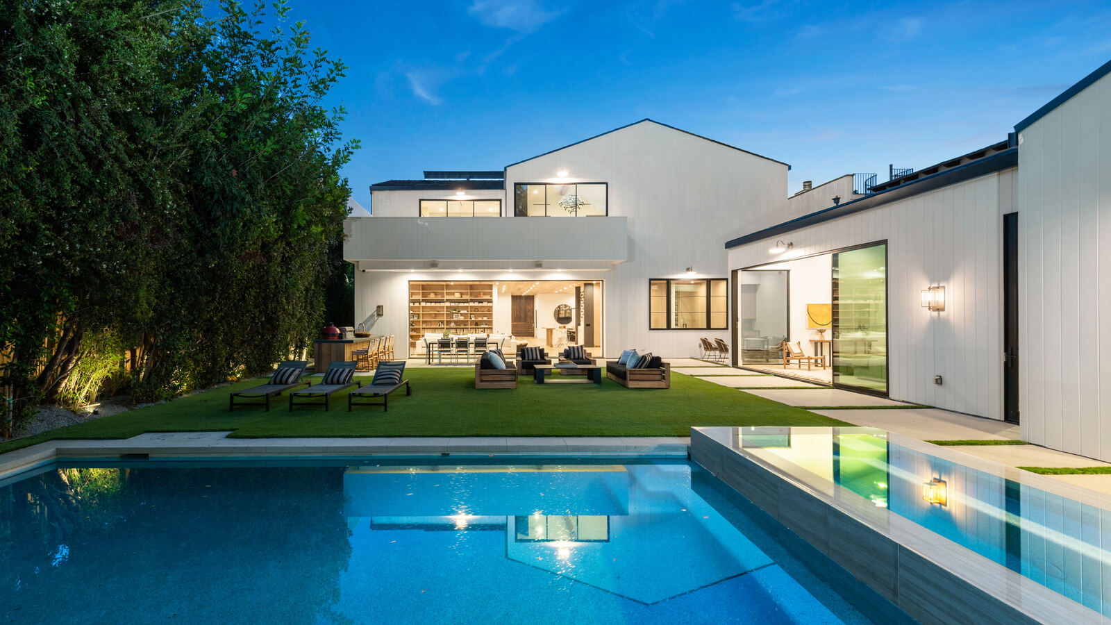 Modern Los Angeles home with illuminated backyard pool at dusk