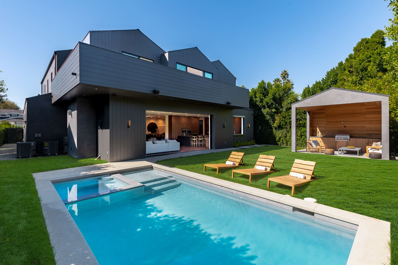 Modern Los Angeles backyard with pool, lawn and charcoal home exterior