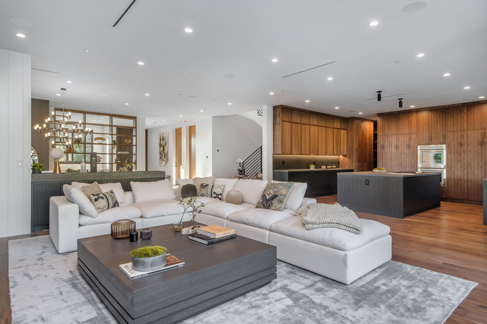 Open Los Angeles living room with white sectional and wood kitchen