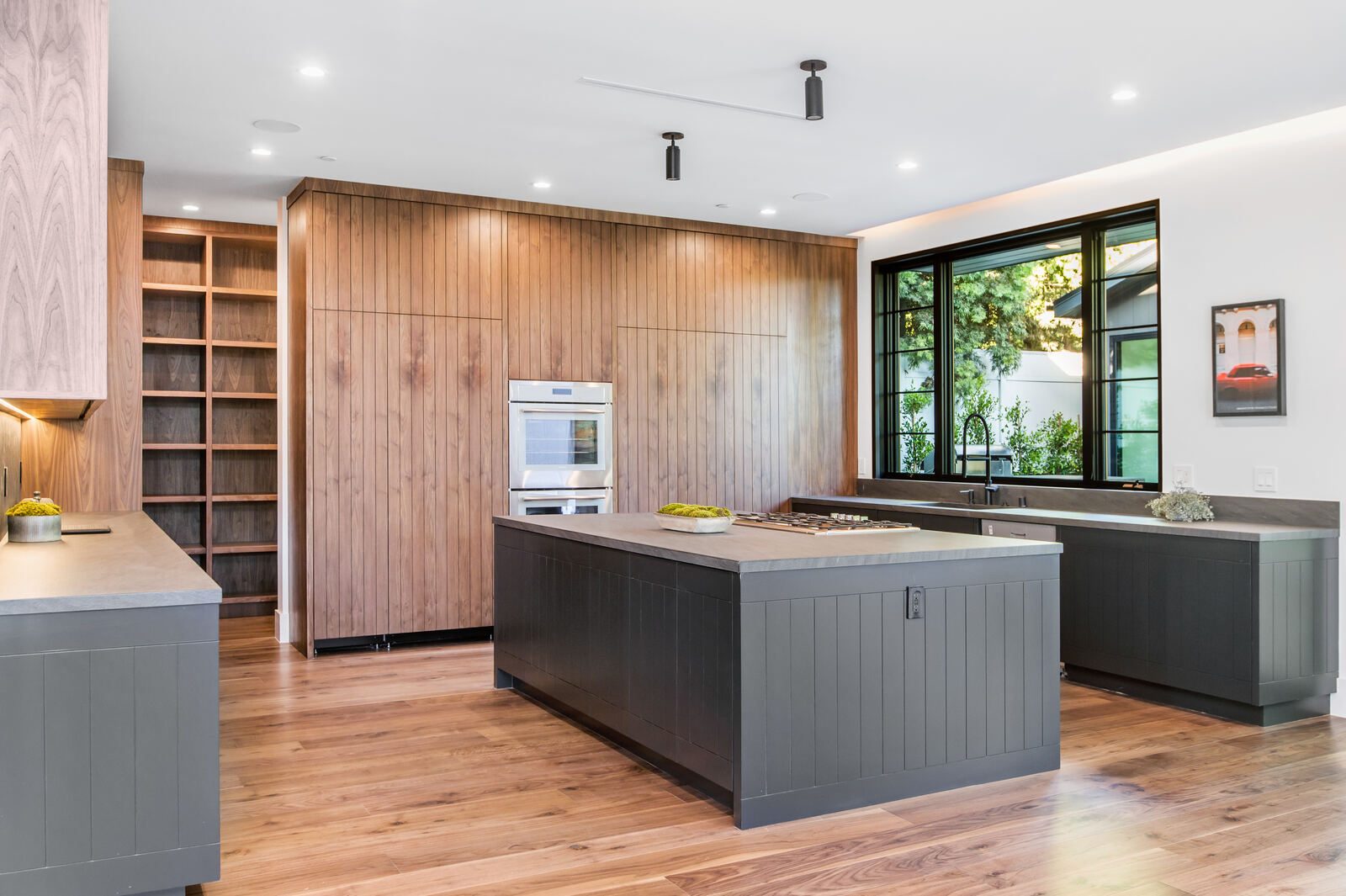 Wood kitchen with a paneled island and large black-framed window in Los Angeles